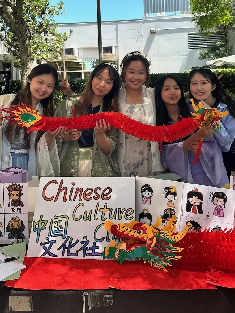 Officers in hanfu holding a paper dragon behind the club booth at Club Row