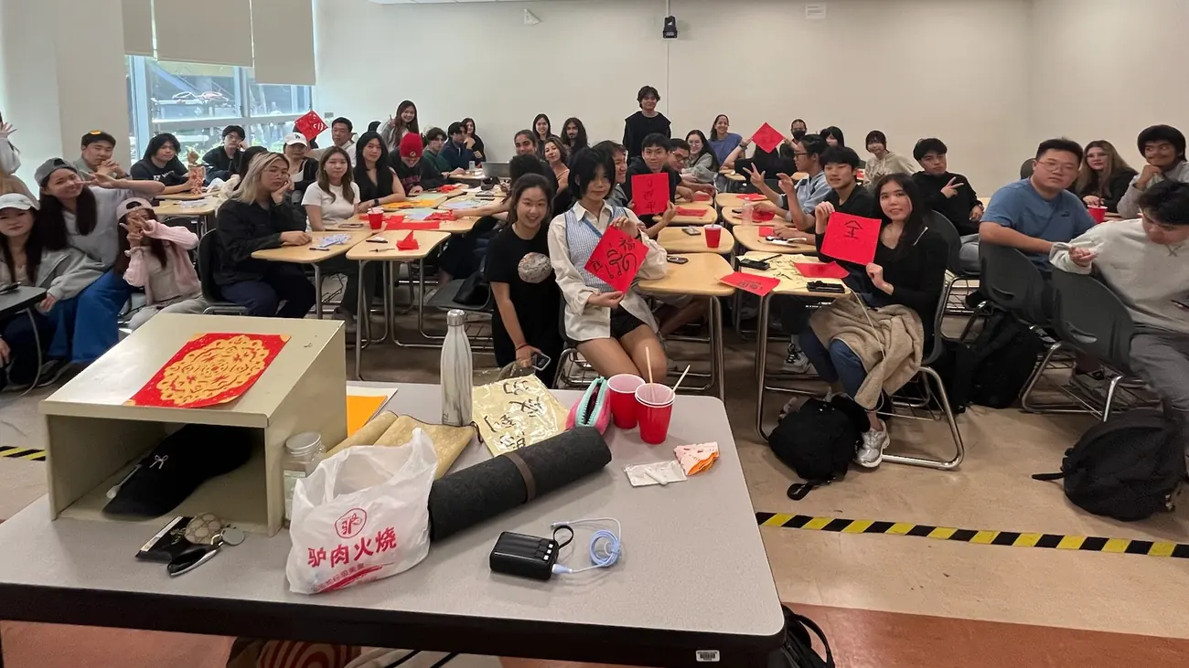 A full classroom holding up red calligraphy squares and paper-cuts