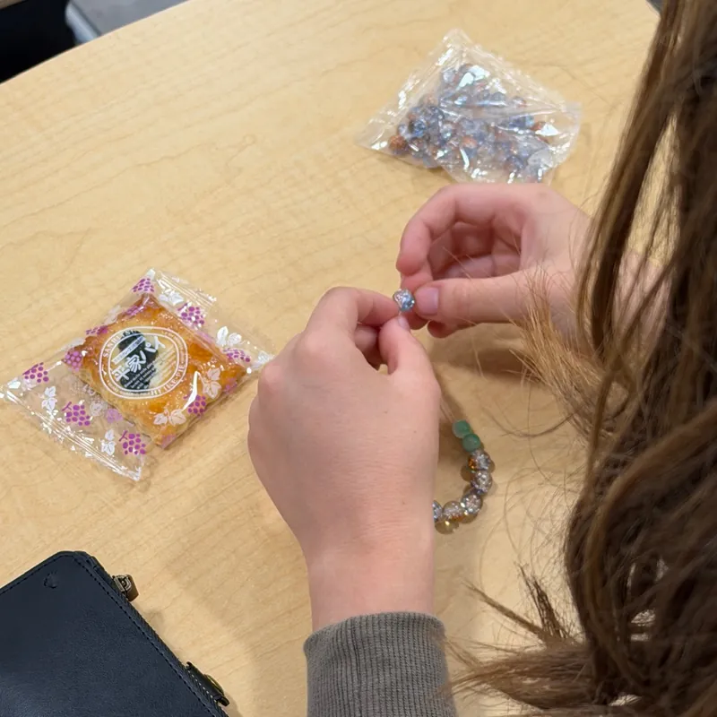 Threading colored-glaze beads onto a bracelet at a meeting