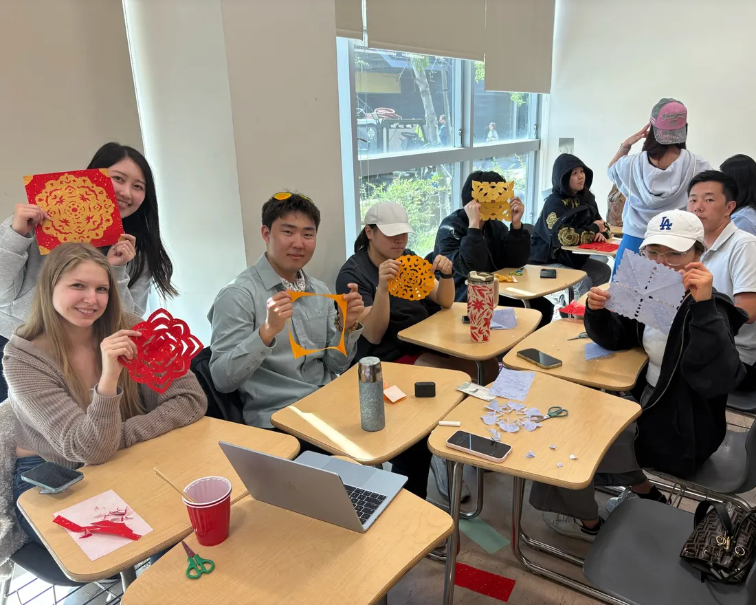 Members holding up the paper-cuts they just made
