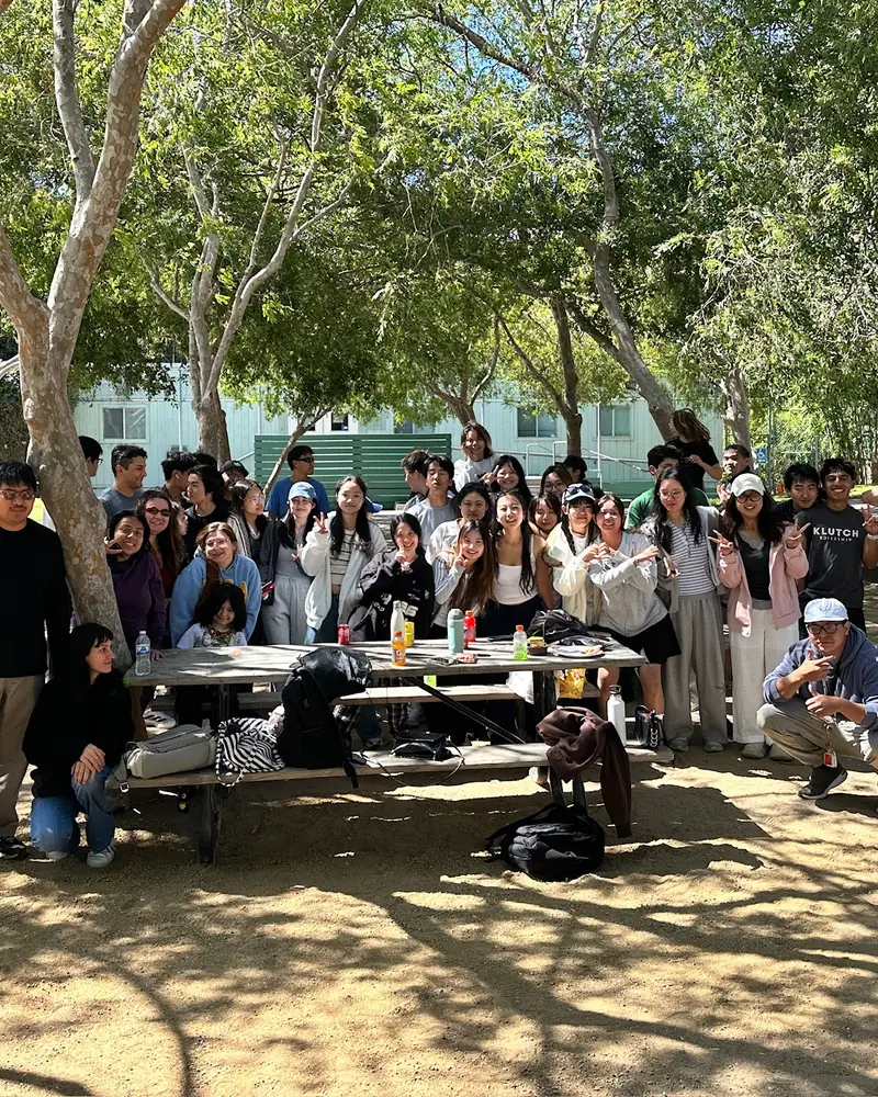 The club gathered around picnic tables under the trees for a potluck